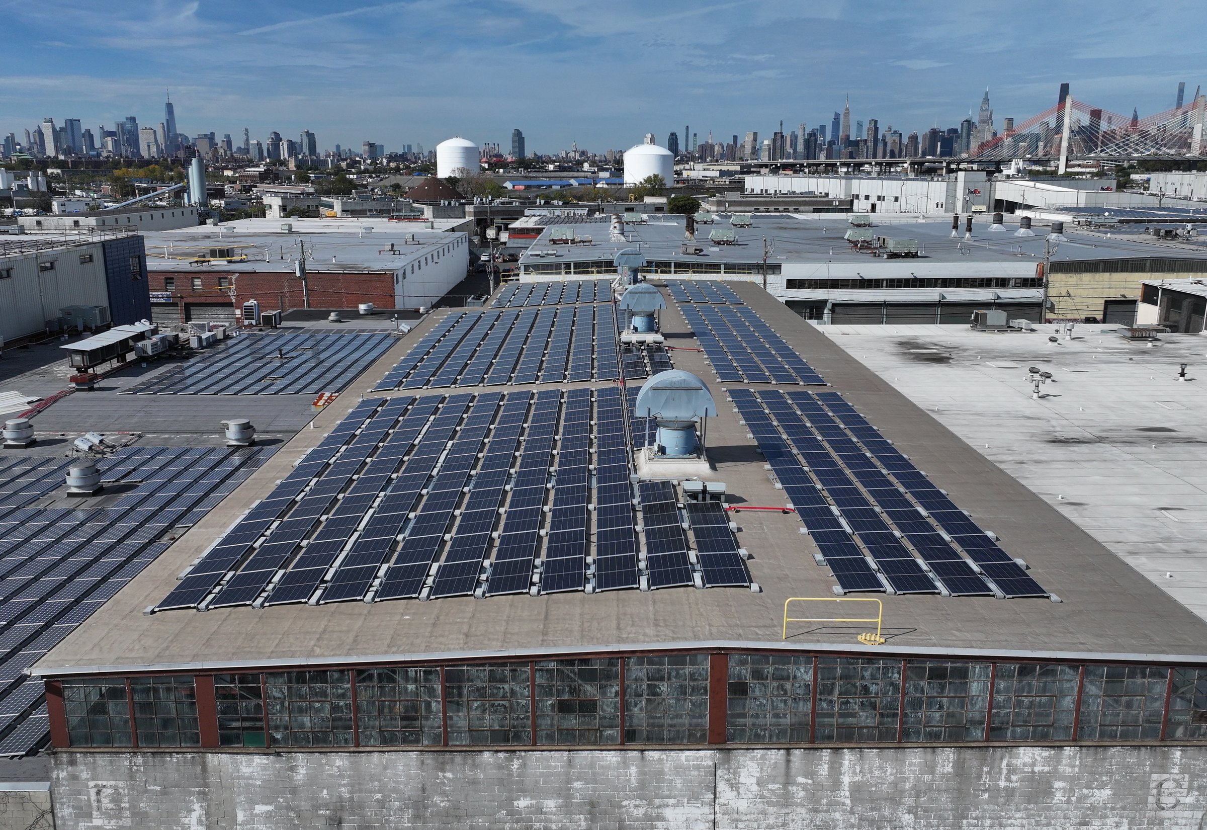 Rooftop solar array at the Maspeth food distribution facility with the Manhattan skyline behind it