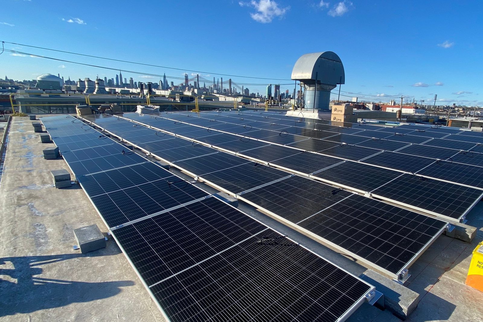 Rooftop solar array in Maspeth, Queens with the Manhattan skyline behind it