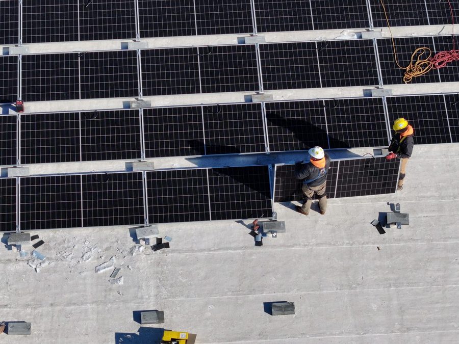 Crew setting panels on a commercial roof, seen from above