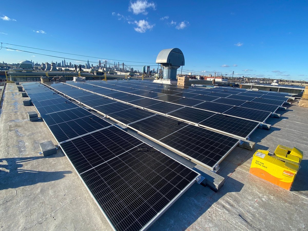 Rooftop solar array in Maspeth with the Manhattan skyline behind it