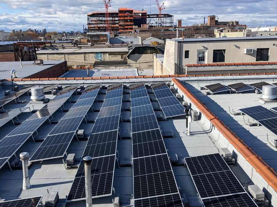 Rooftop solar array with construction cranes behind it